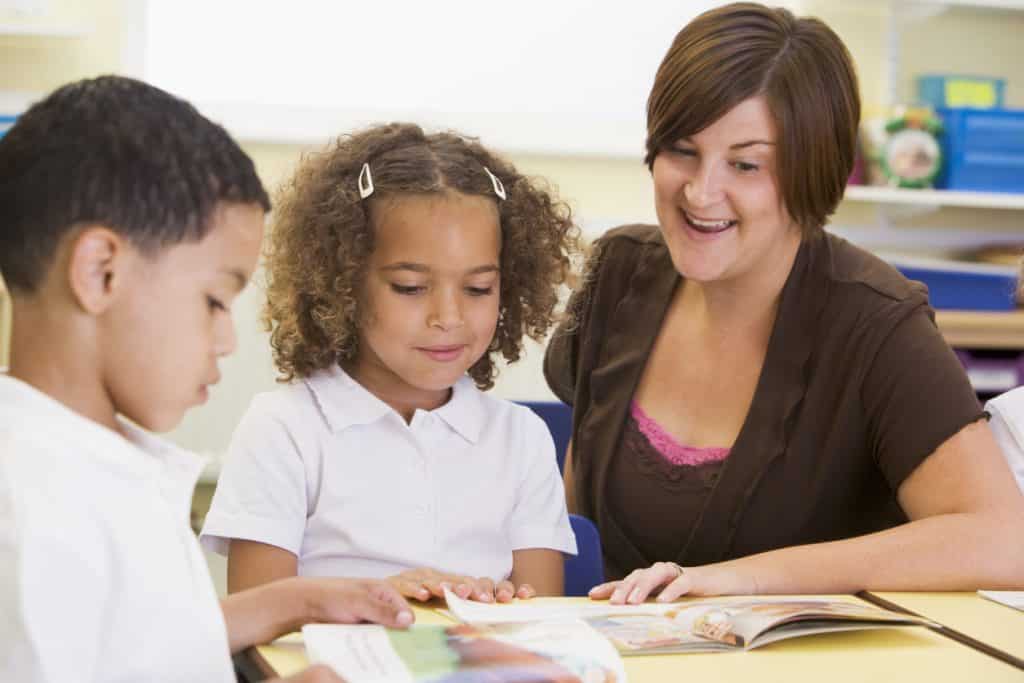 Two young children and their teacher reading