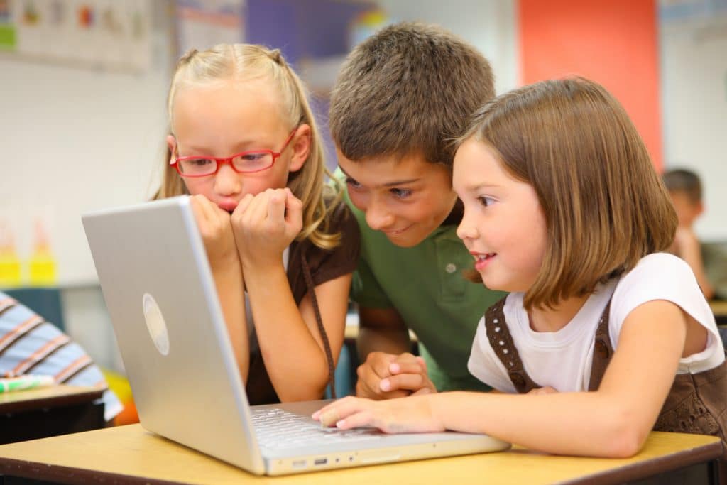 Elementary school students look at laptop computer children